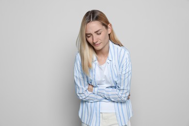 Photo of Young woman suffering from menstrual pain on light grey background