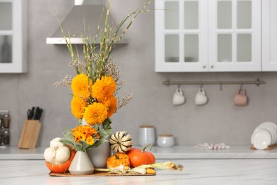 Beautiful autumn bouquets and pumpkins on marble table in kitchen