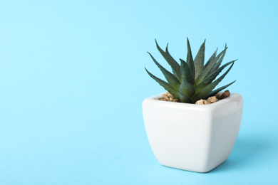 Photo of Beautiful artificial plant in flower pot on light blue background, space for text