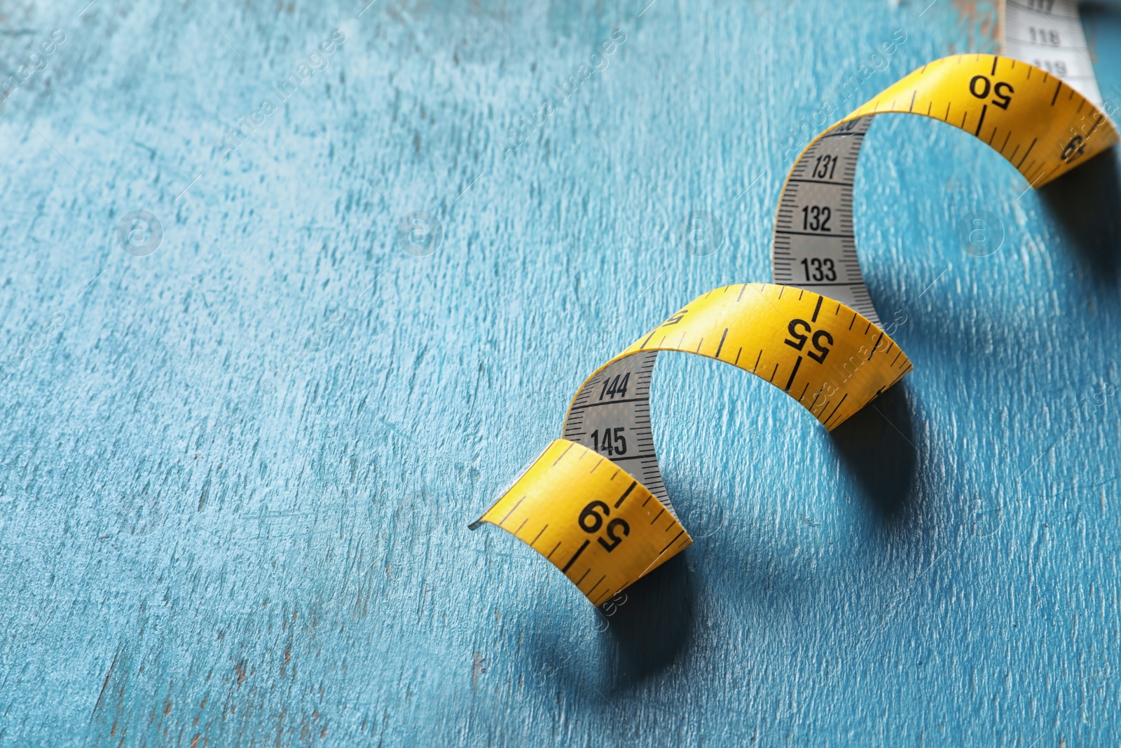 Photo of Measuring tape on wooden background, closeup. Tailoring equipment