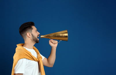 Young man with megaphone on blue background