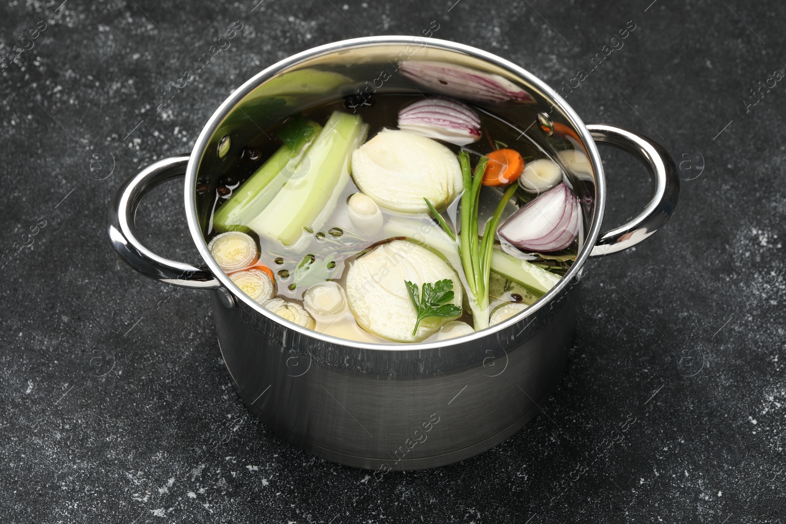 Photo of Different ingredients for cooking tasty bouillon in pot on black table