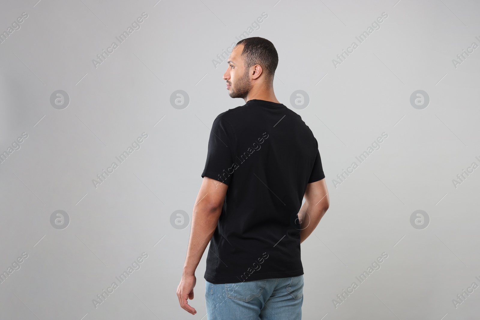Photo of Man wearing black t-shirt on gray background, back view