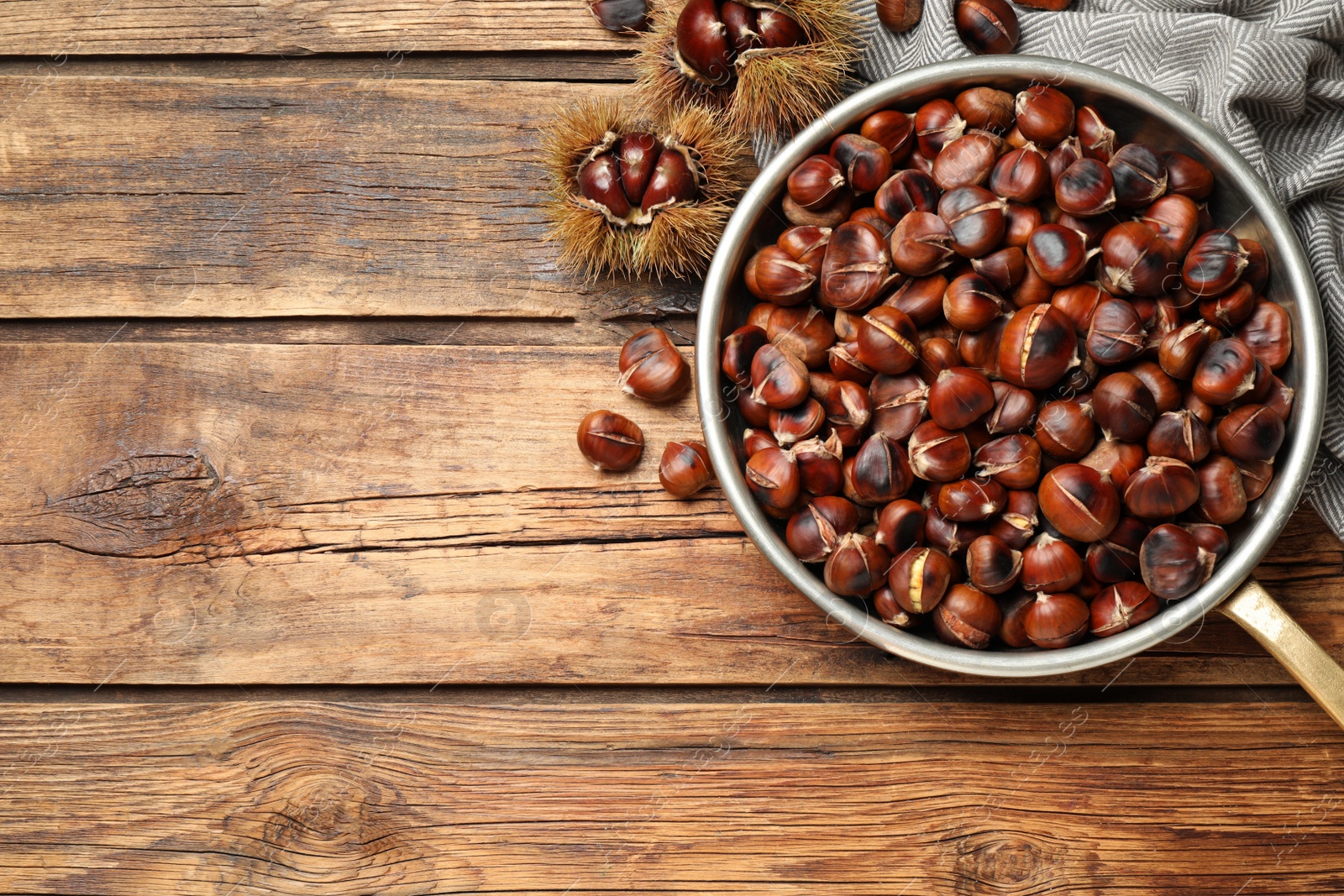 Photo of Delicious roasted edible chestnuts on wooden table, flat lay. Space for text