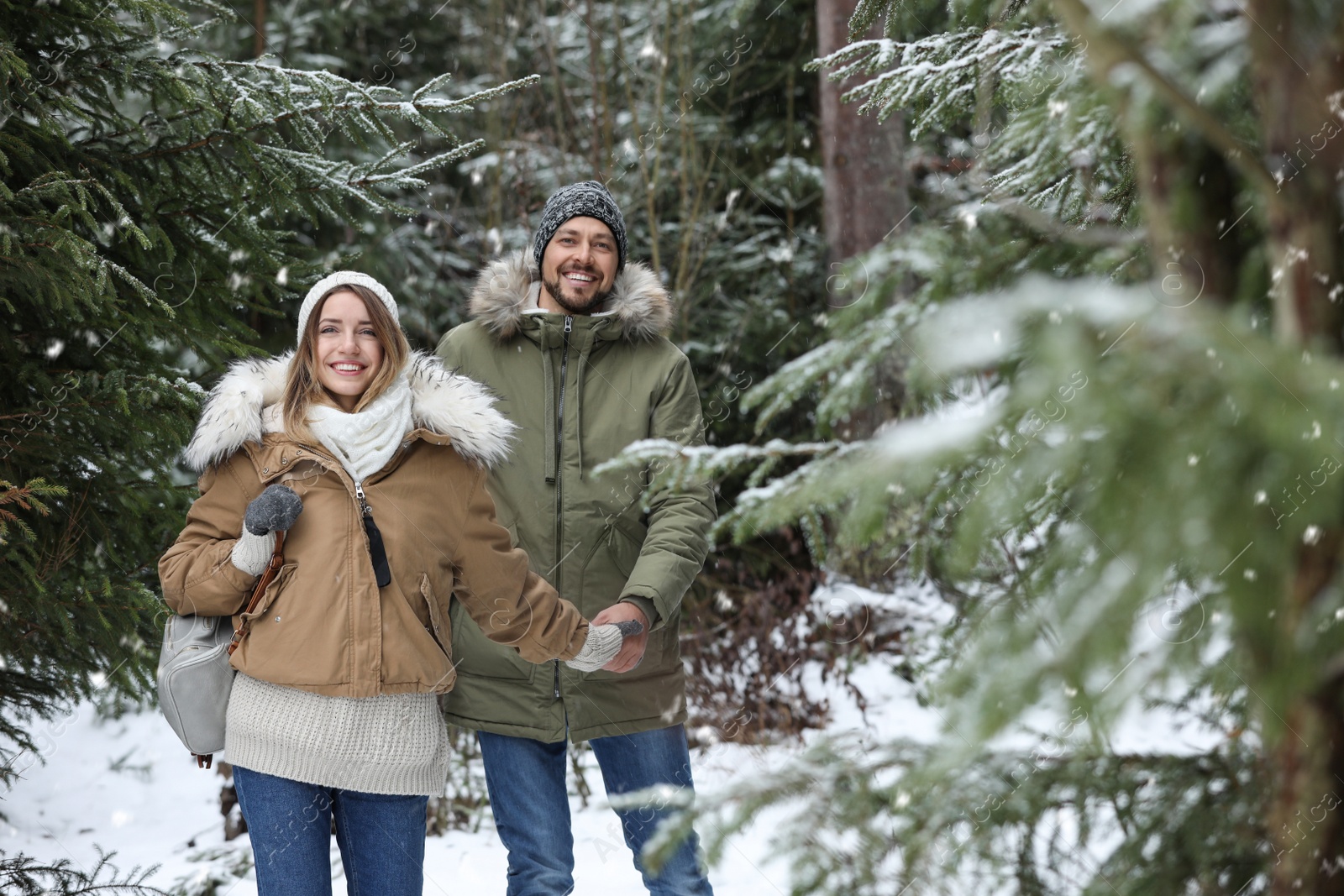 Photo of Couple in conifer forest on snowy day, space for text. Winter vacation