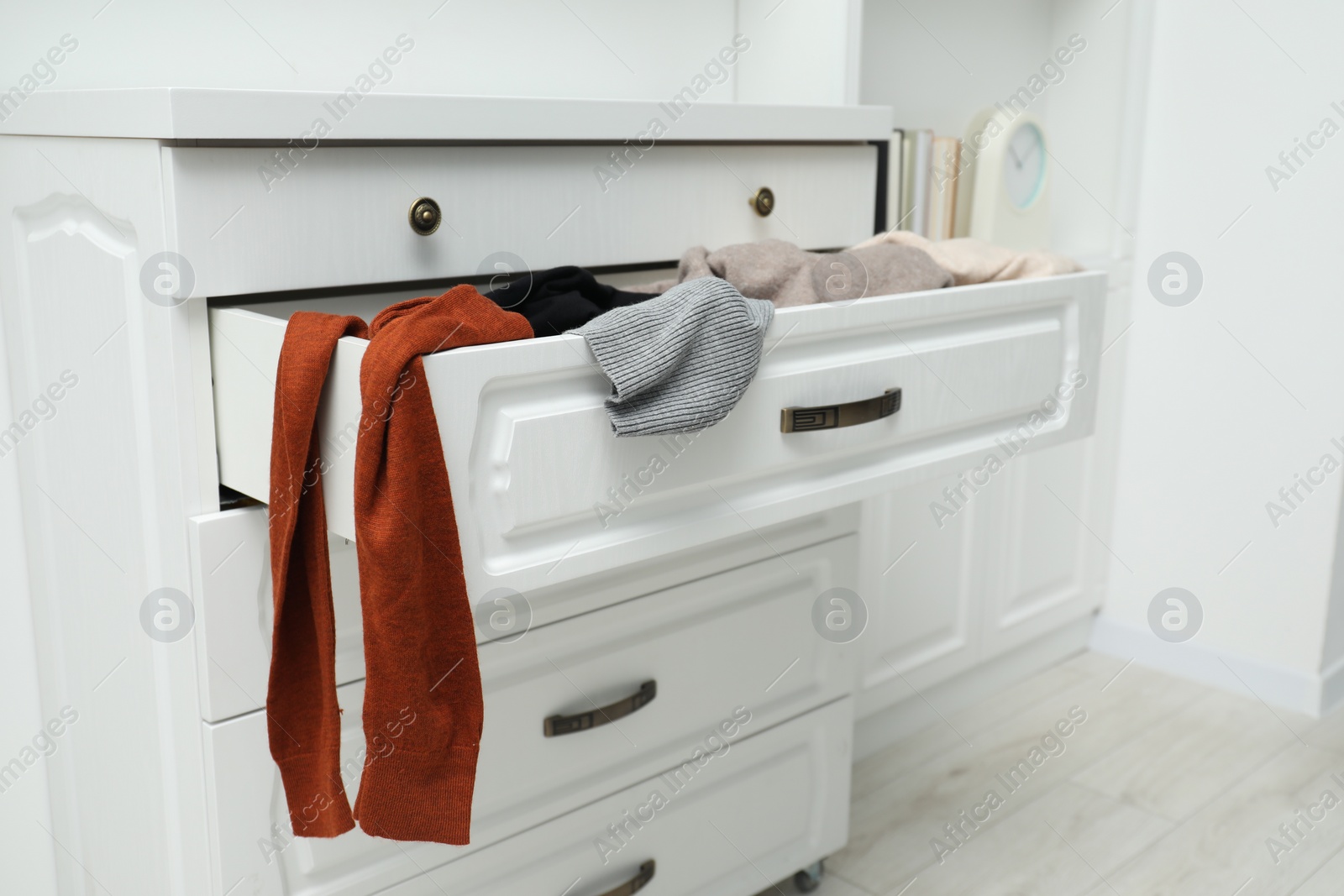 Photo of Cluttered chest of drawers indoors. Clothes in mess