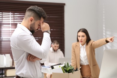 Boss dismissing young man from work in office