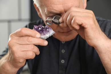 Photo of Male jeweler evaluating semi precious gemstone in workshop, closeup