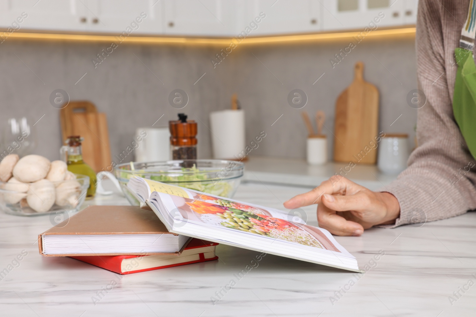 Photo of Woman with recipe book at table in kitchen, closeup