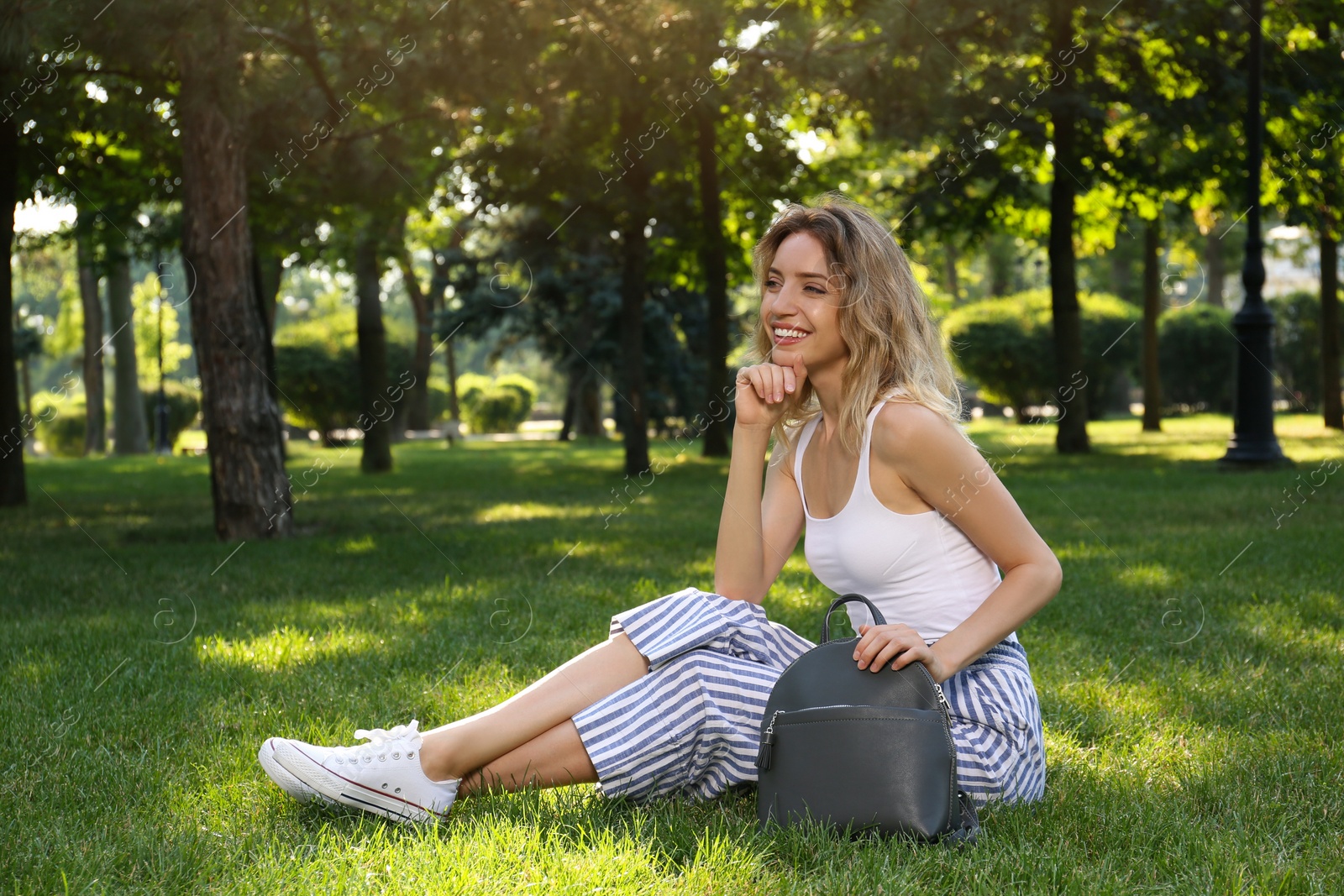 Photo of Young woman with stylish backpack in park