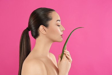 Photo of Young woman with aloe vera leaf on pink background