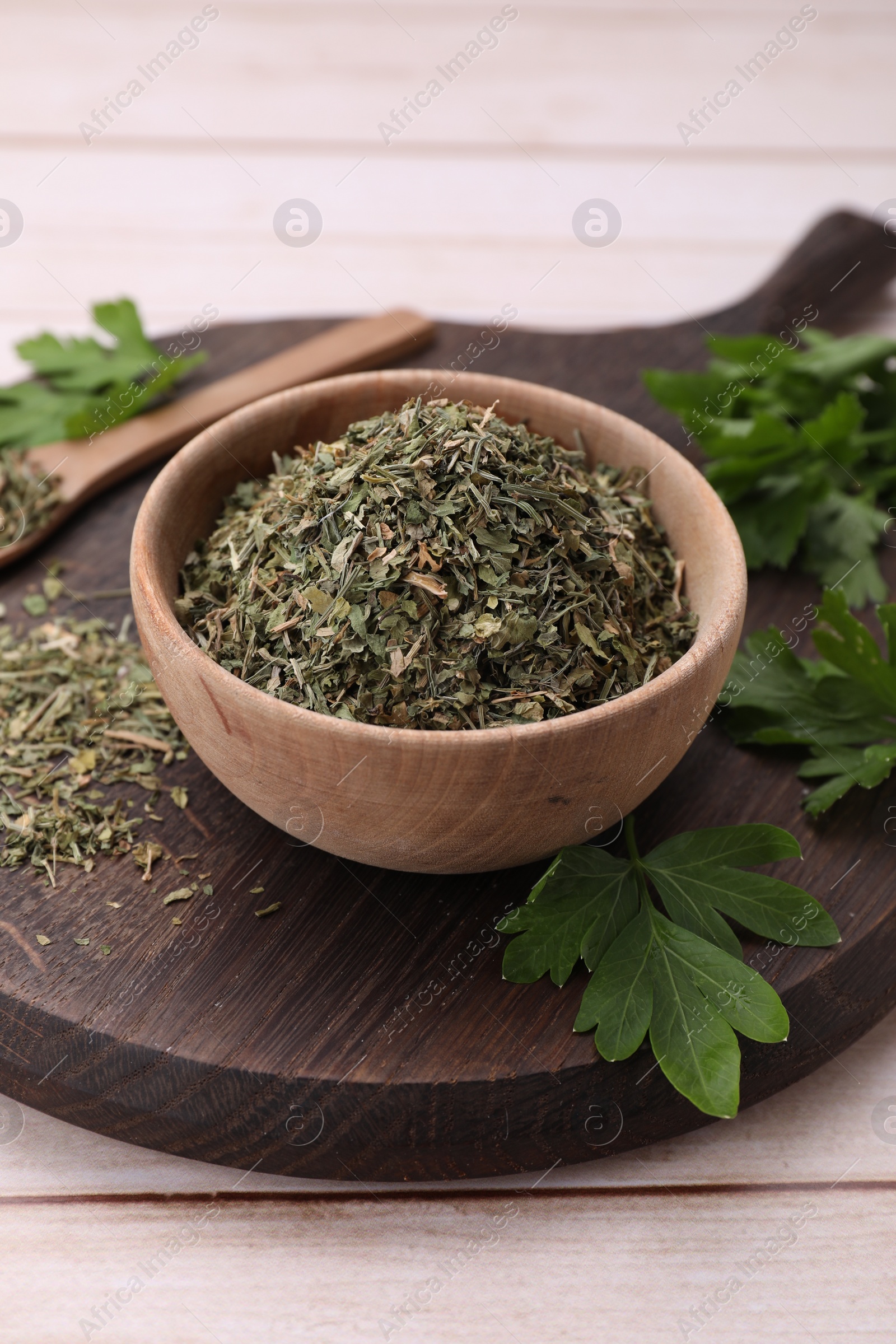 Photo of Dried aromatic parsley and fresh leaves on white wooden table