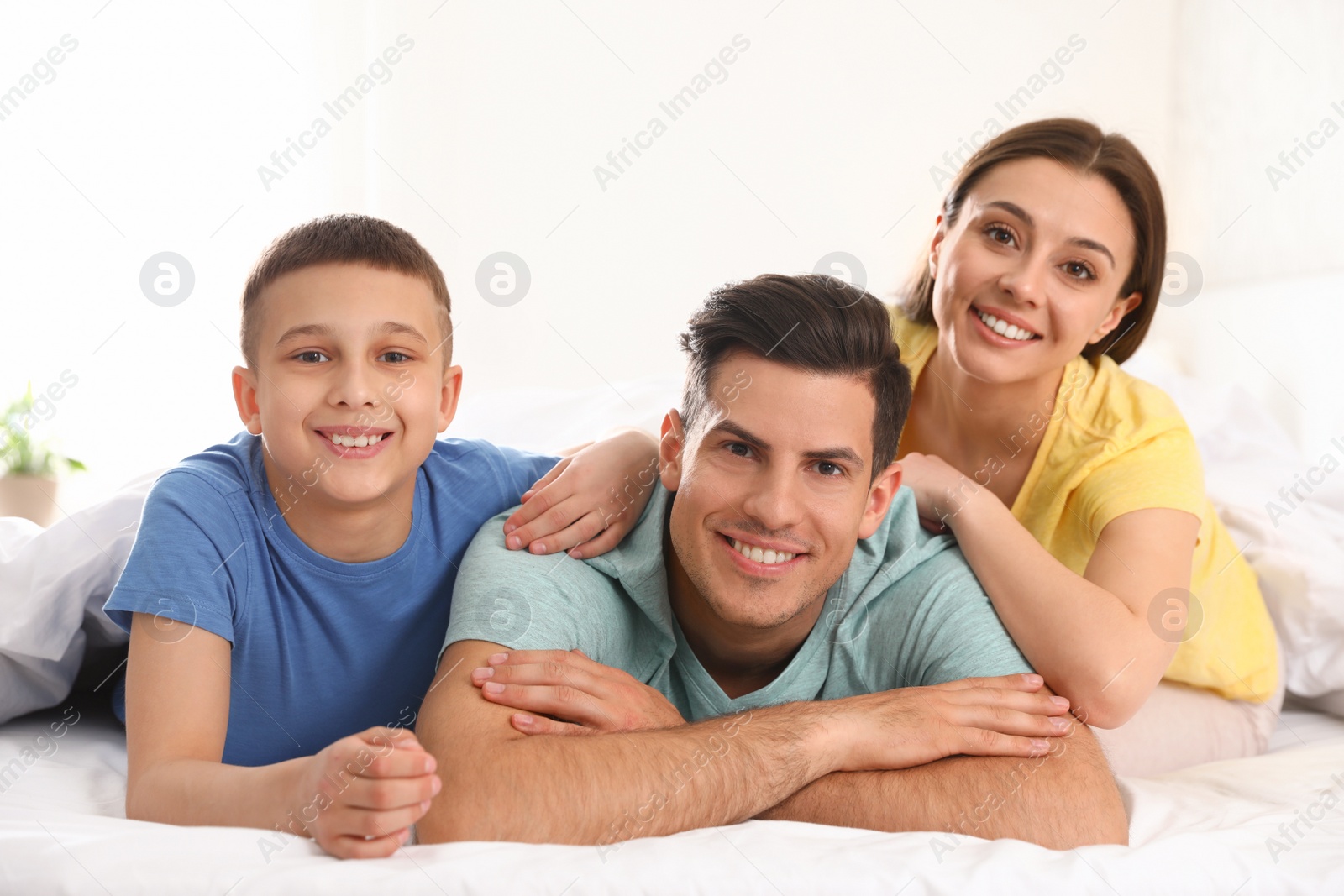 Photo of Happy young family together on large bed