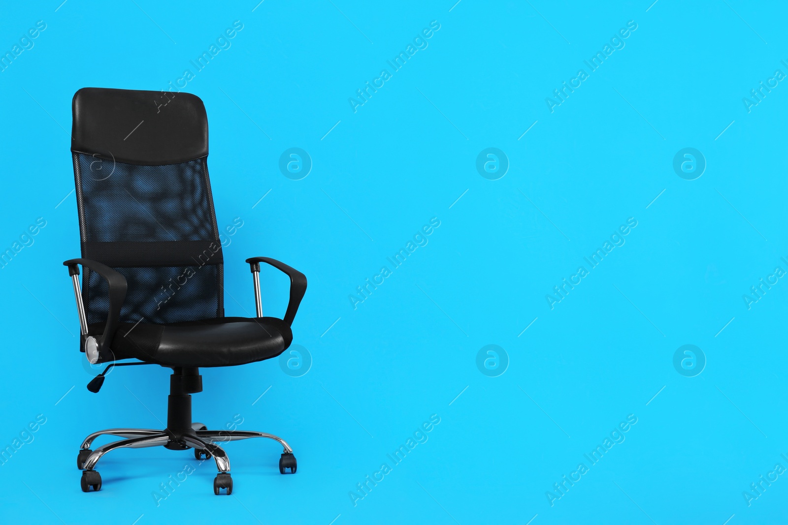 Photo of Comfortable office chair on light blue background, space for text