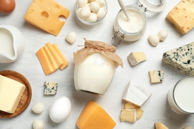 Photo of Different delicious dairy products on white table, flat lay