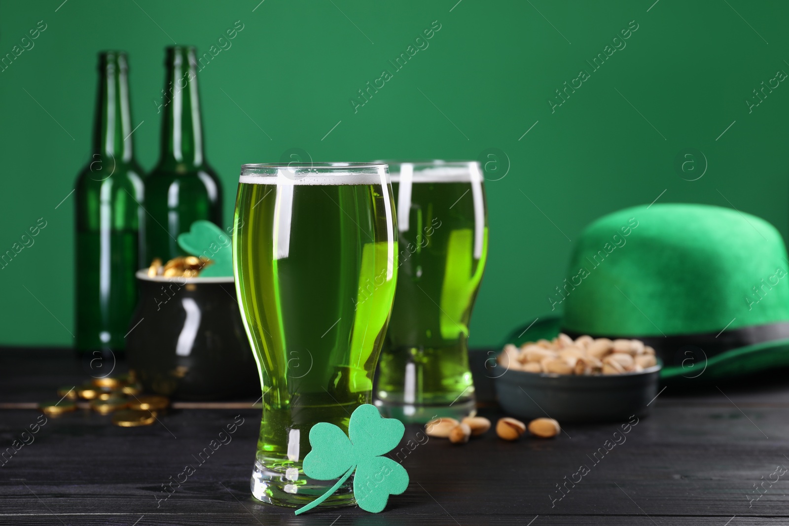 Photo of St. Patrick's day party. Green beer, leprechaun hat, pot of gold, pistachios and decorative clover leaf on wooden table