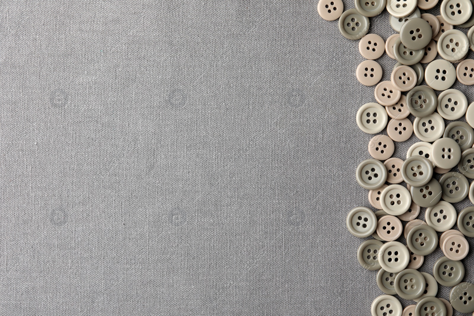 Photo of Many plastic sewing buttons on grey fabric, flat lay. Space for text