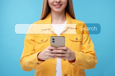 Search bar of website over smartphone. Woman using device on light blue background, closeup
