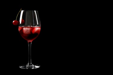 Delicious cherry wine with ripe juicy berries on black background. Space for text