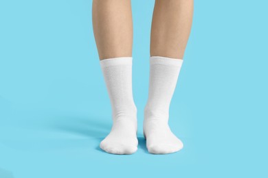 Photo of Woman in stylish white socks on light blue background, closeup