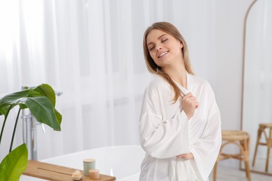 Beautiful happy woman wearing stylish white robe in light bathroom