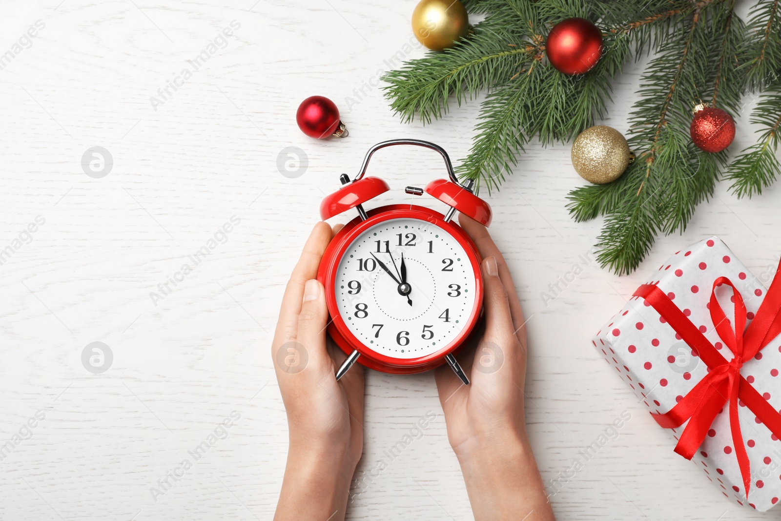 Photo of Woman holding retro alarm clock on table. Christmas countdown