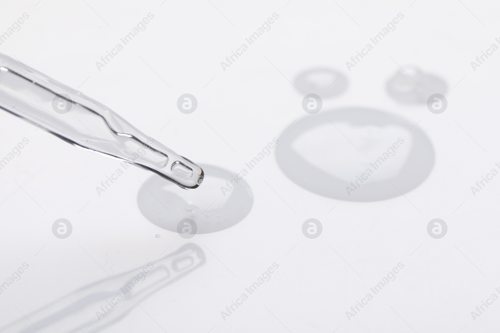 Photo of Glass pipette and transparent liquid on white background, closeup