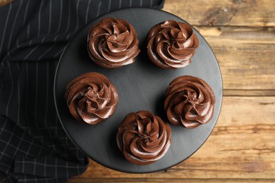 Dessert stand with delicious chocolate cupcakes on wooden table, top view