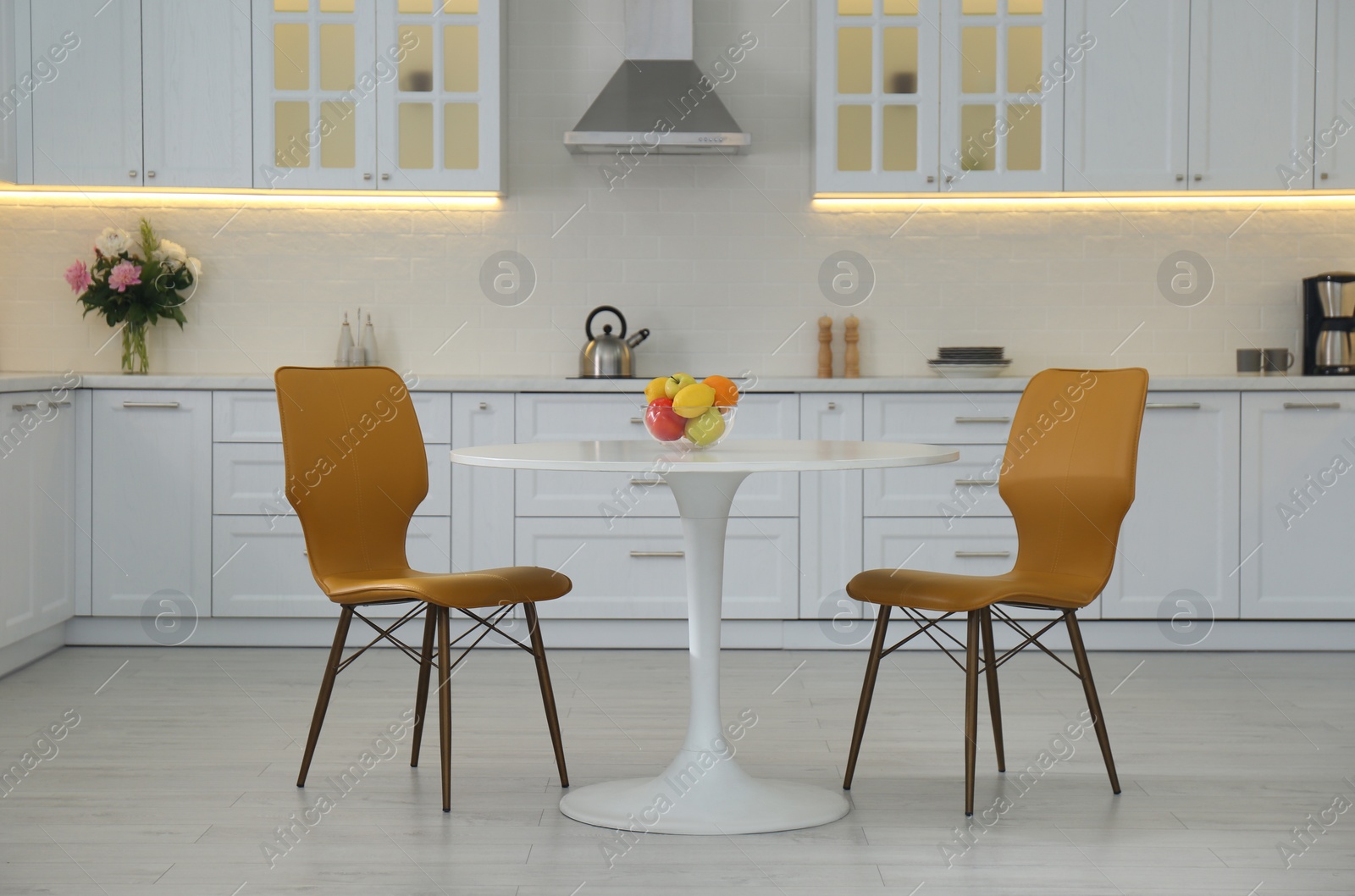 Table with orange chairs in modern kitchen interior Photo of Table with orange chairs in modern kitchen interior
