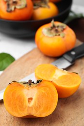 Photo of Whole and cut delicious ripe persimmons on table, closeup