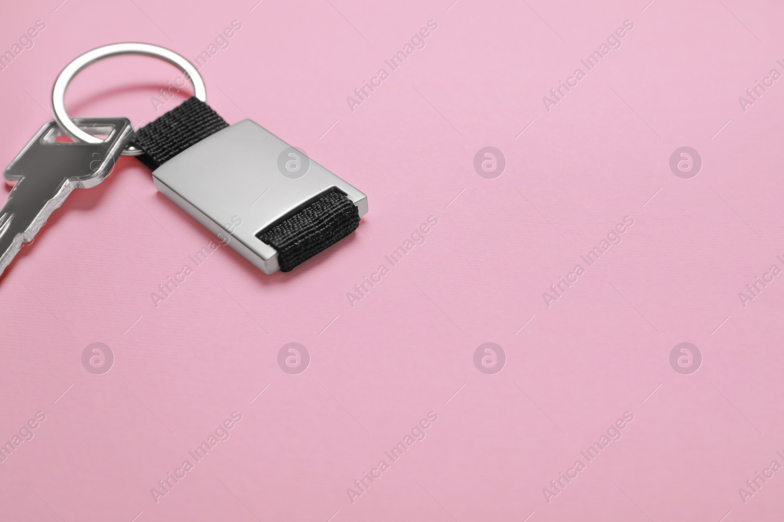 Photo of Key with metallic keychain on pale pink background, space for text