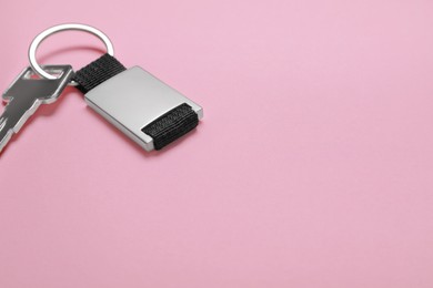 Photo of Key with metallic keychain on pale pink background, space for text
