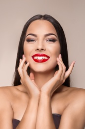 Photo of Portrait of beautiful young woman with red glossy lips on color background