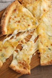 Delicious cut cheese pizza on wooden table, top view