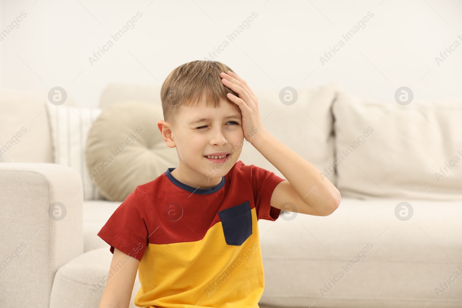 Photo of Little boy suffering from headache at home