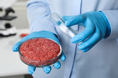 Photo of Scientist holding Petri dish with minced cultured meat in laboratory, closeup