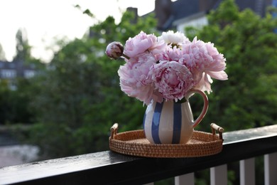 Beautiful pink peony flowers in vase on balcony railing outdoors. Space for text