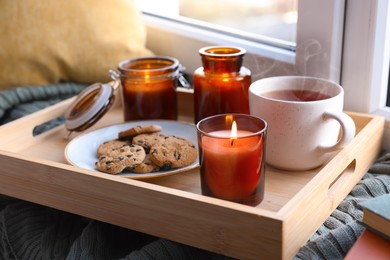 Photo of Breakfast tray with burning candles near window indoors