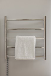 Photo of Heated rail with towel on white wall in bathroom