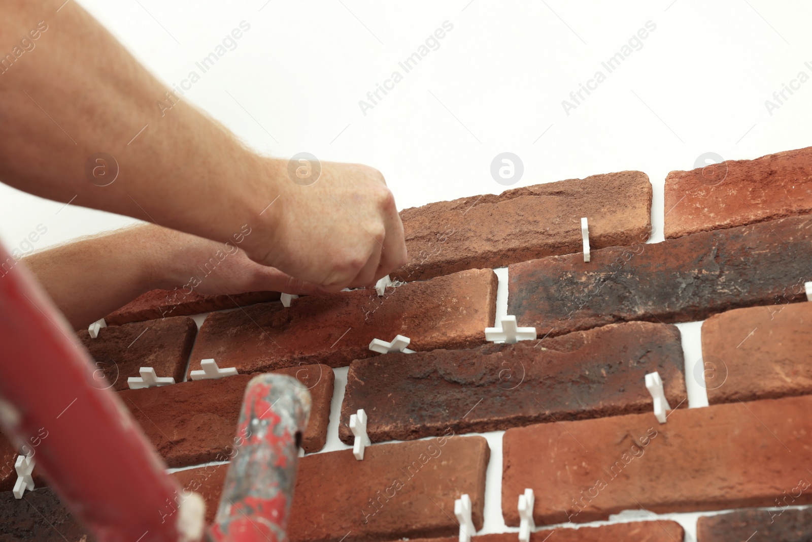 Photo of Professional builder gluing decorative brick on wall, closeup. Tiles installation process