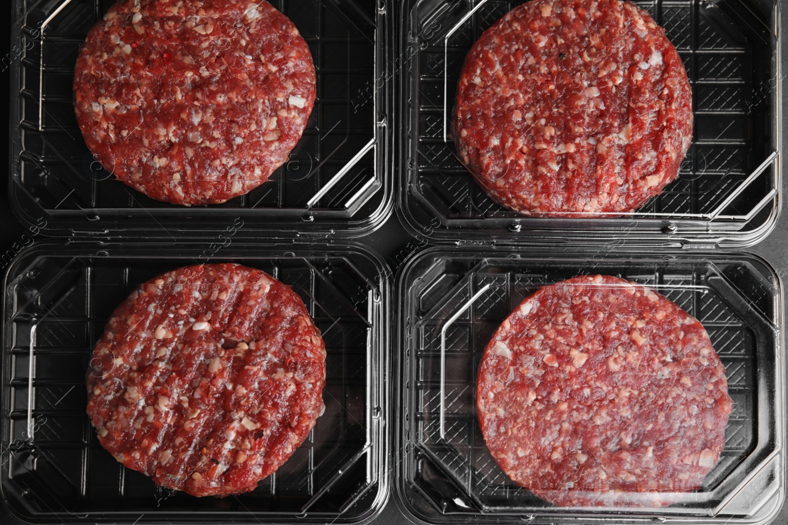 Photo of Plastic containers with raw meat cutlets for burger, top view