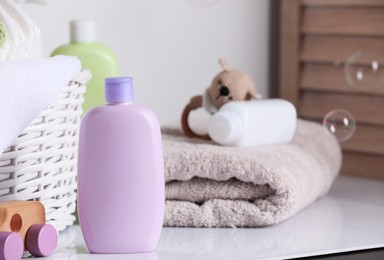 Baby cosmetic products, toys and towel on white table