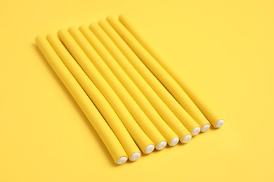 Curling rods on yellow background. Hair styling tool
