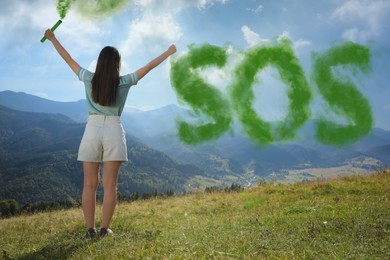 Image of Woman and word SOS made of color smoke bomb in mountains, back view