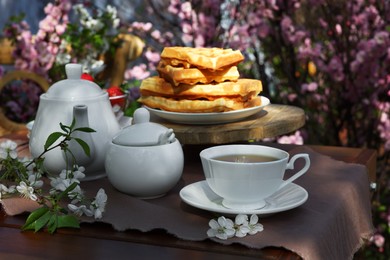 Beautiful spring flowers and freshly baked waffles on table served for tea drinking in garden