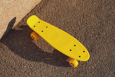 Stylish yellow skateboard on asphalt outdoors, above view