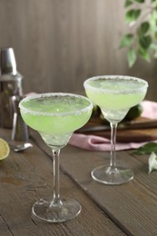 Delicious Margarita cocktail in glasses on wooden table, closeup