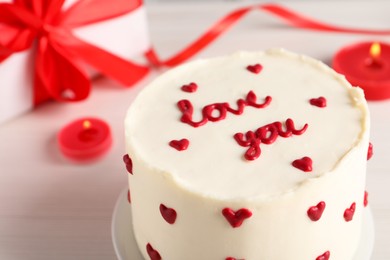 Photo of Bento cake with text Love You, candles and gift box on white table, closeup. St. Valentine's day surprise