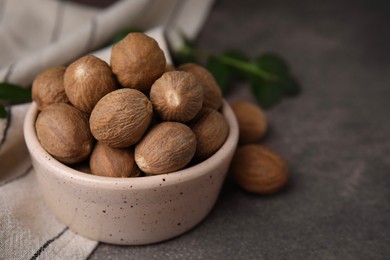 Photo of Whole nutmegs in bowl on brown table, closeup. Space for text