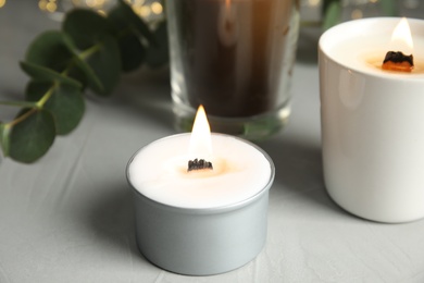 Burning scented candles on light grey table